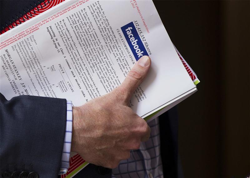 A man stands outside of the St. Regis hotel holding a pamphlet of information on investing in the upcoming IPO of Facebook in New York